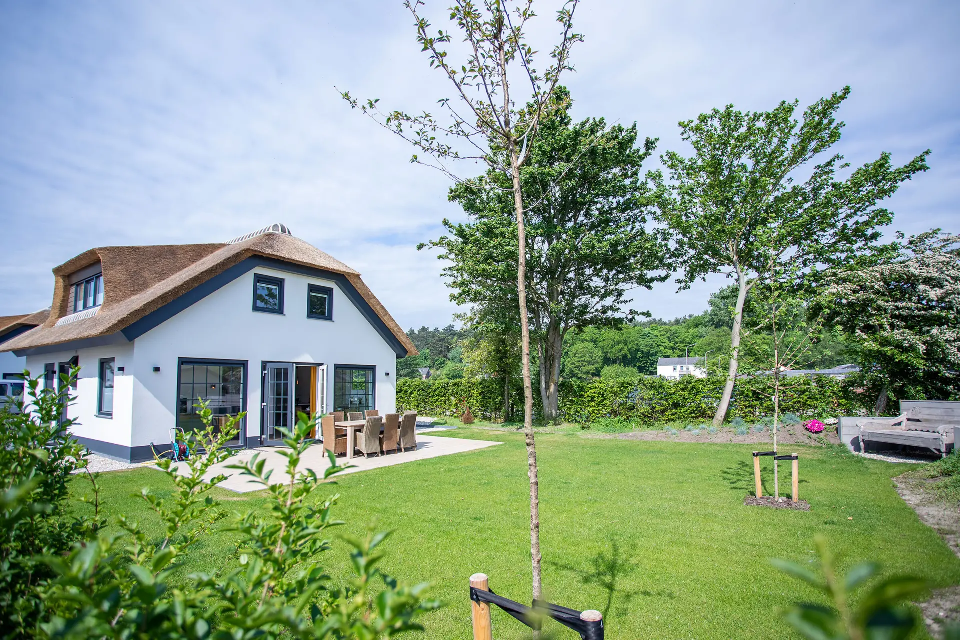 ruime tuin met terras van rietgedekte woning